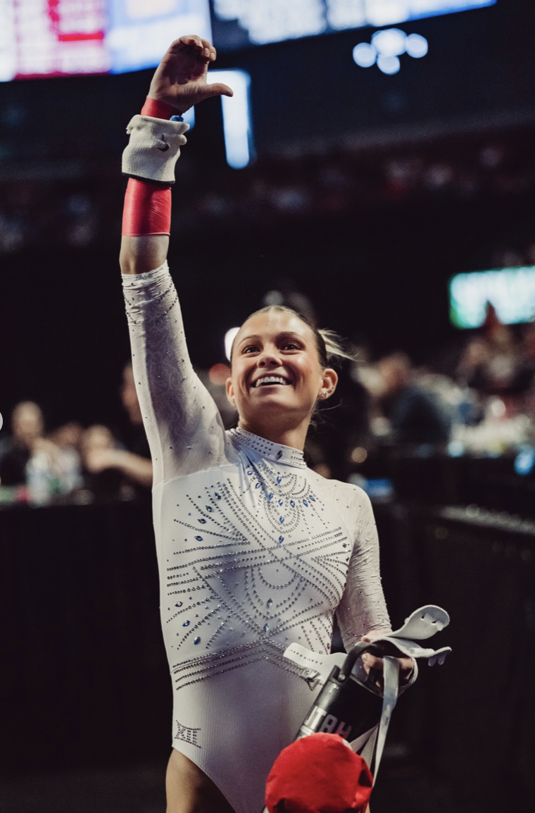 Avery Neff waving after a routine in white leotard