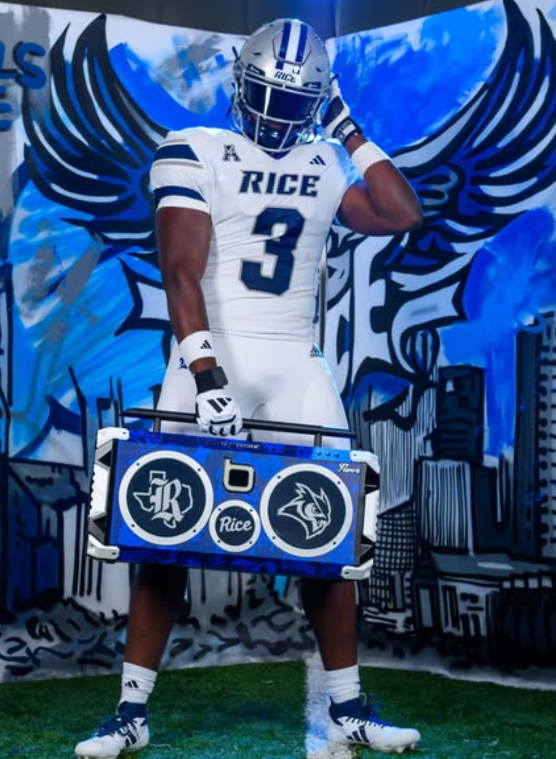 Quincy Tchikou posing in Rice uniform with a custom blue speaker case in front of an owl mural