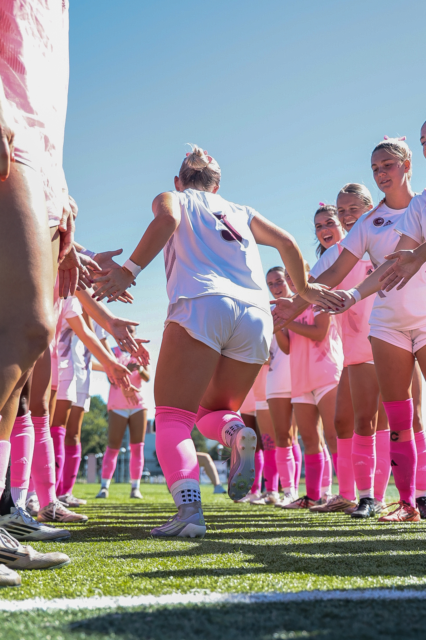 Macee McKenna running through the team tunnel in pink socks for breast cancer awareness