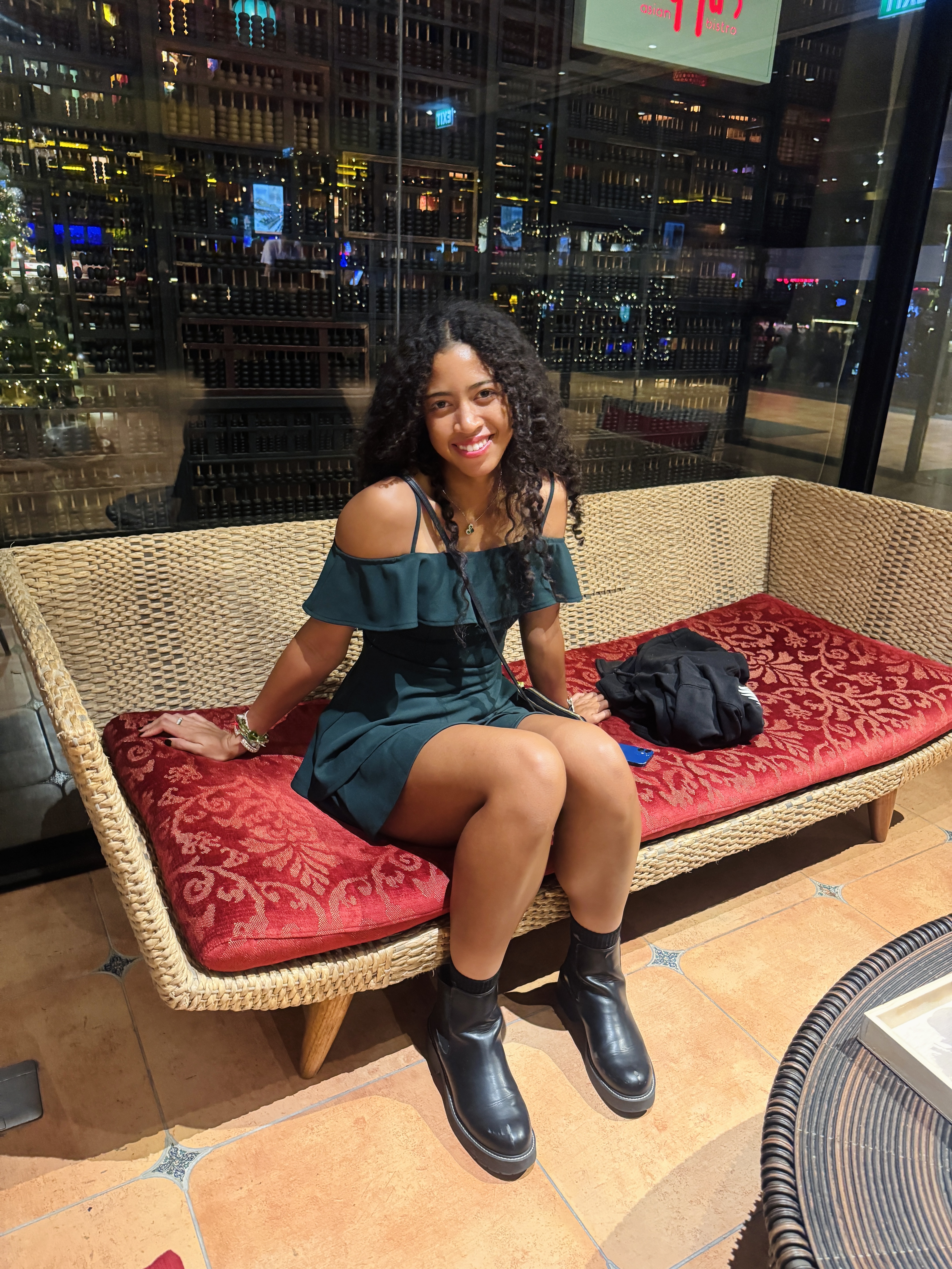Leilani Hereford smiling on a rattan couch at a restaurant with a city view at night
