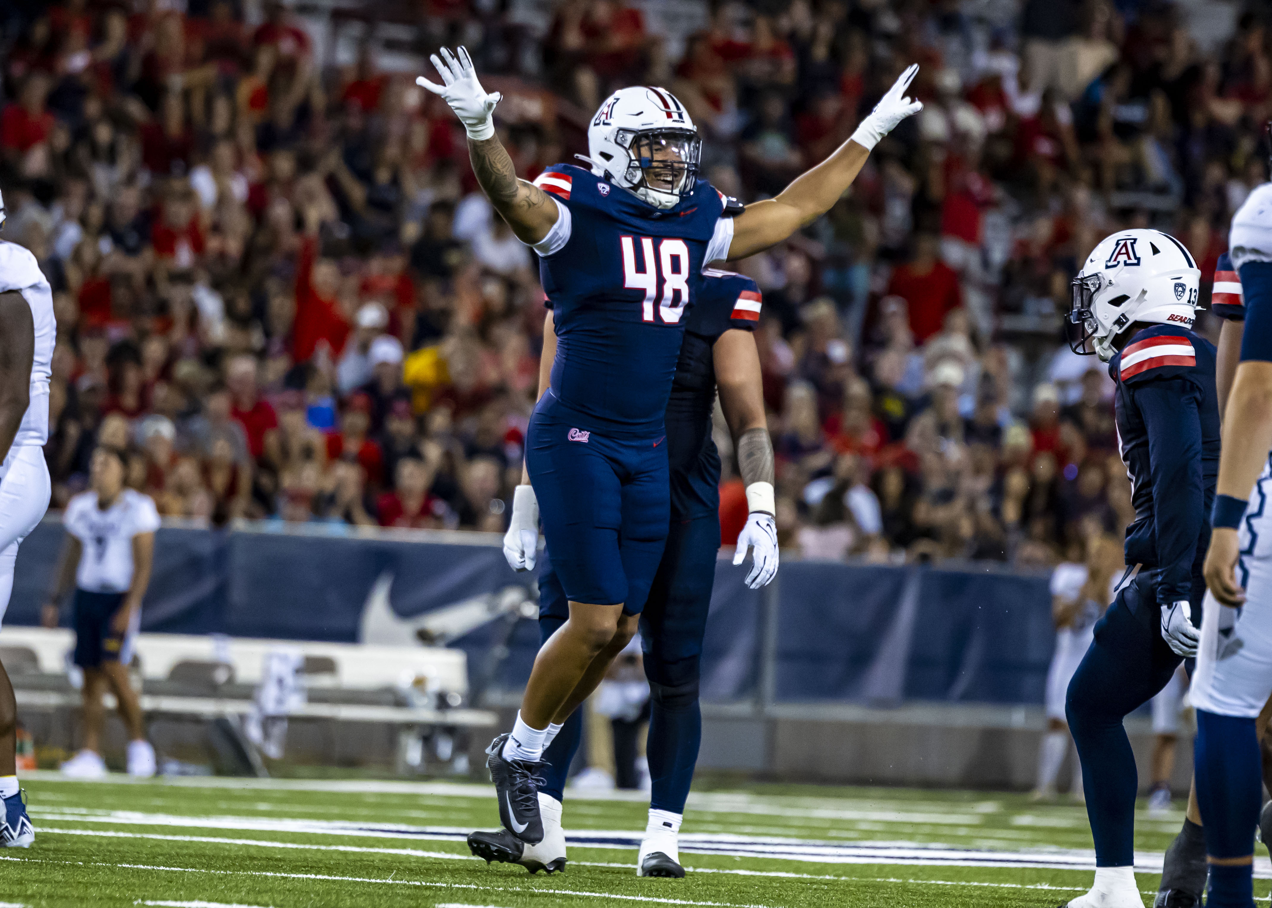 Orin Patu celebrating with arms raised in his Arizona Wildcats home jersey