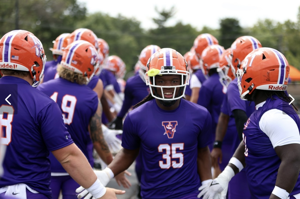 Kylan Wallace walking through teammates in a purple practice uniform