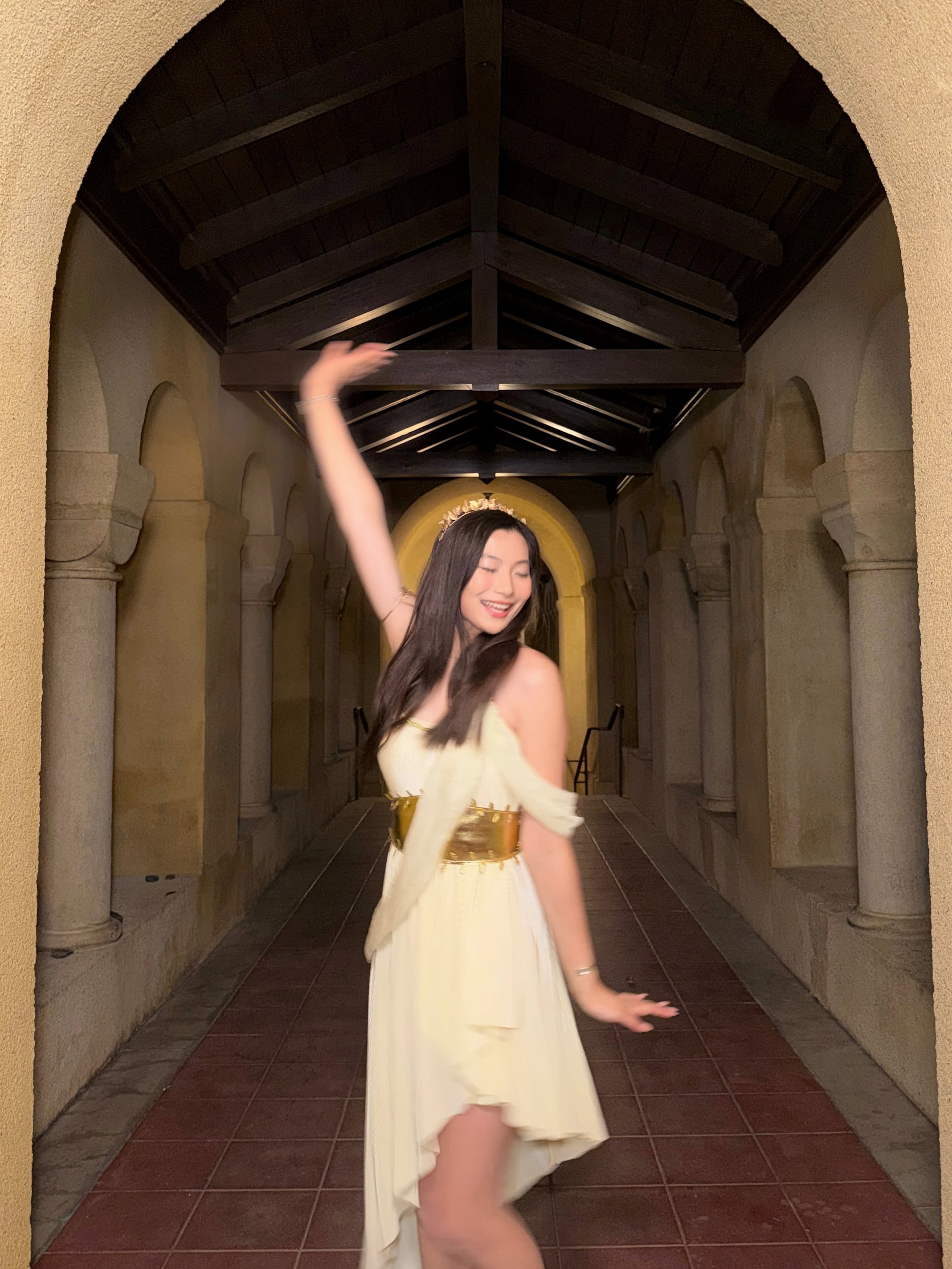 Mia Yilin in a white dress beneath arched walkways