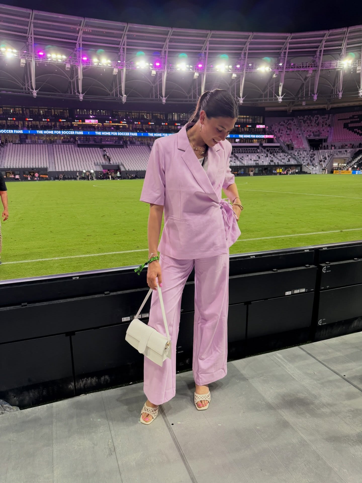 Céline Dept in a lilac suit pitchside at a soccer stadium
