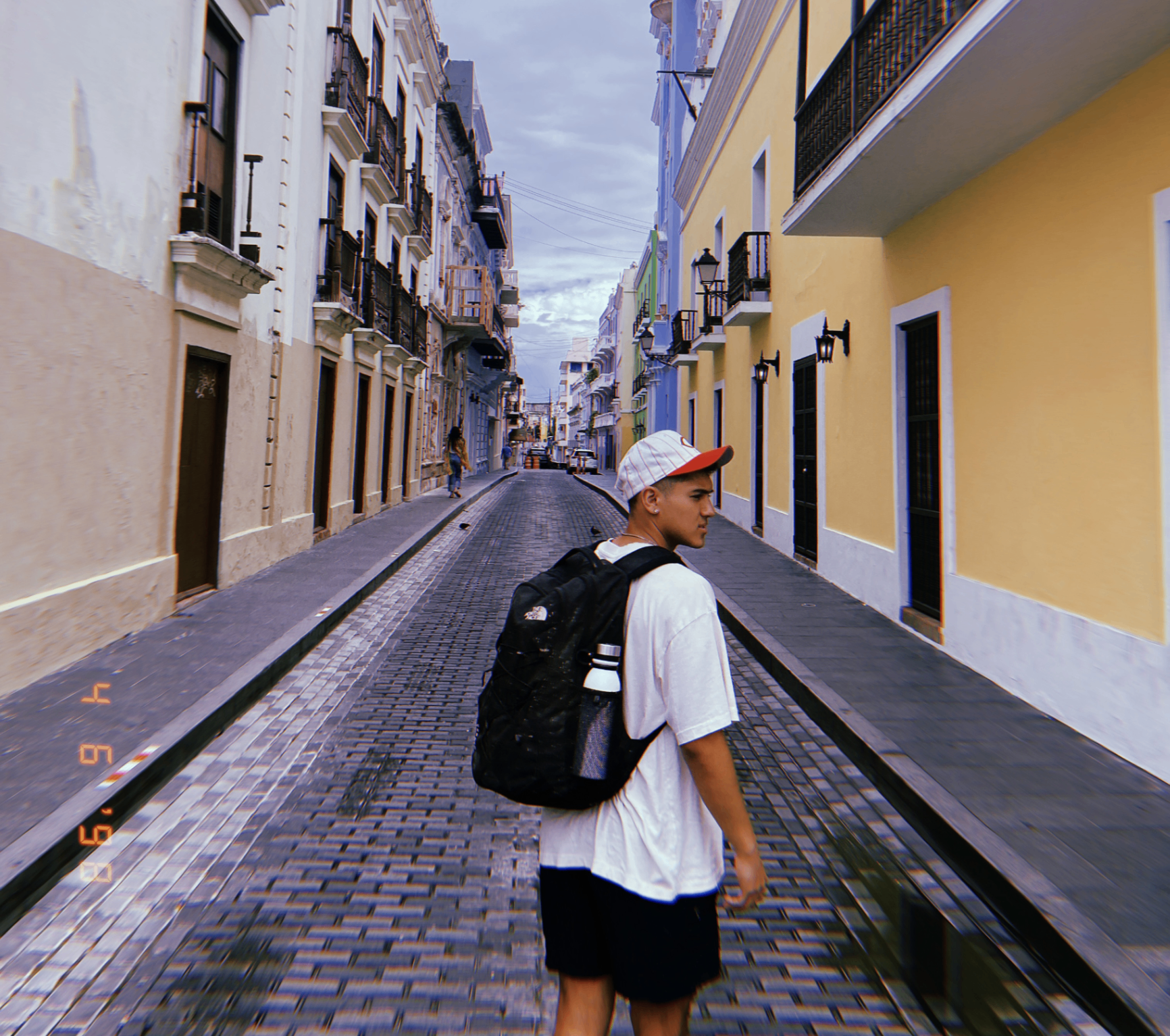 Abraham Arellano walking through a Puerto Rico street with a backpack