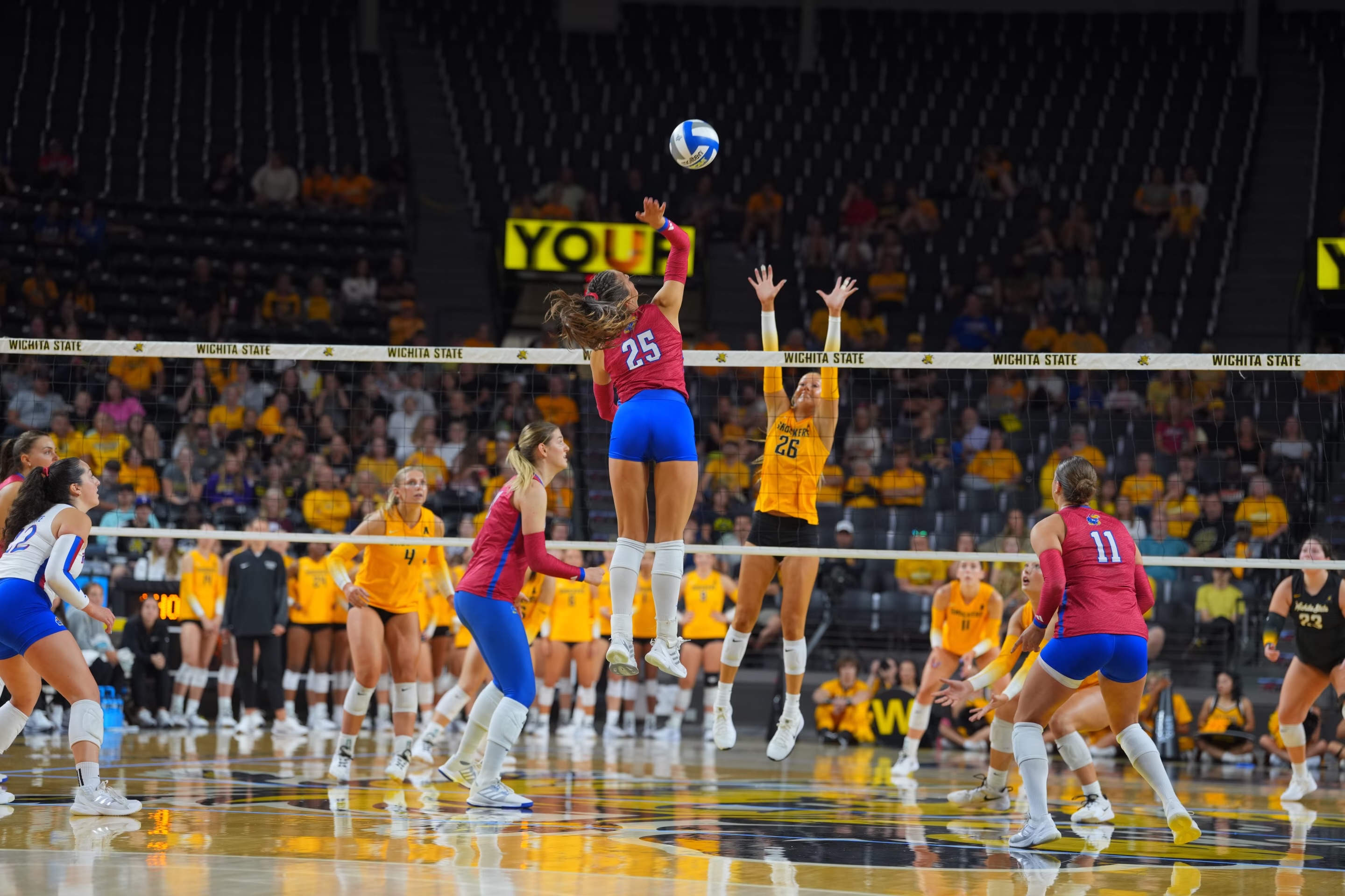 Logan Bell spiking a volleyball over the net during a Kansas match