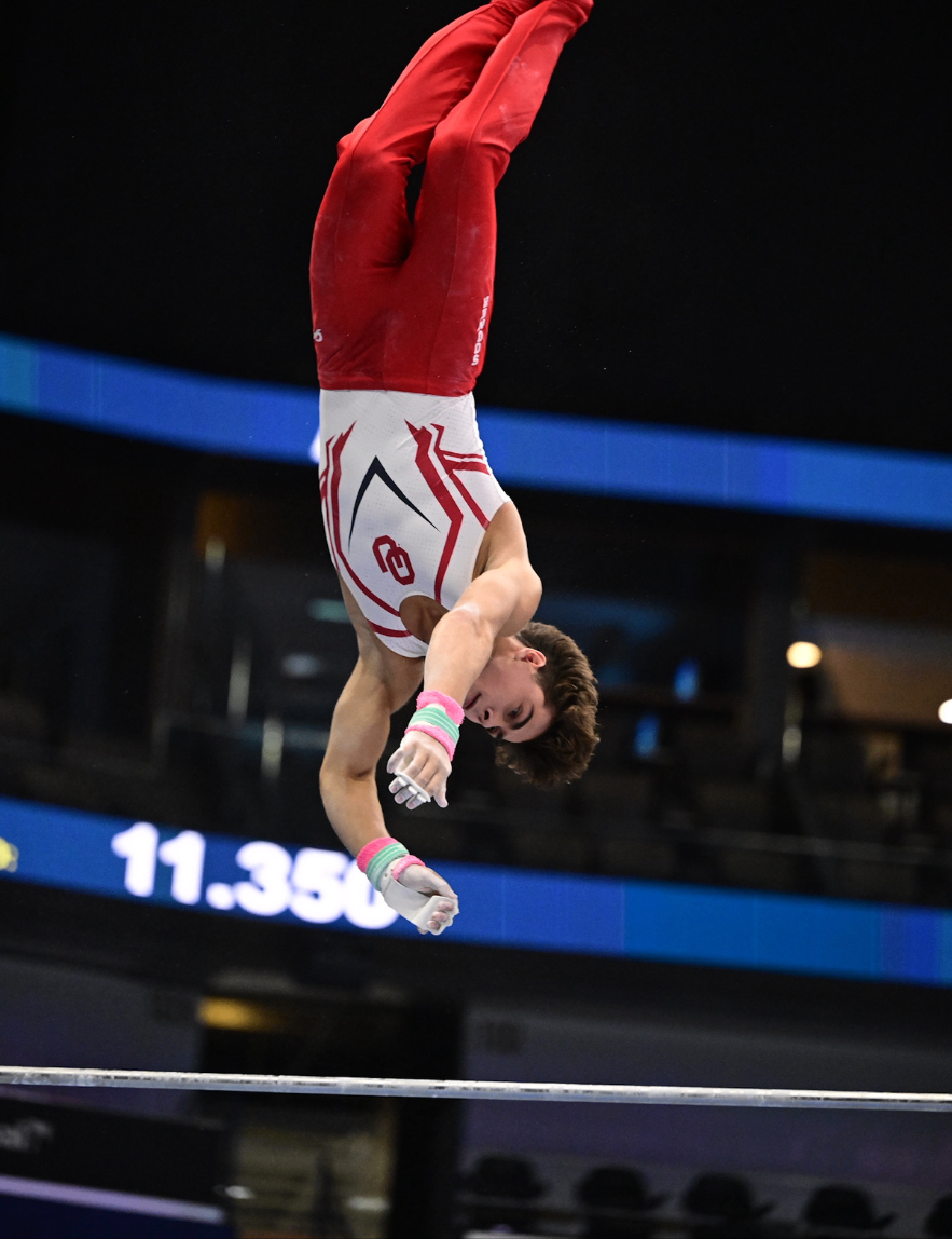 Alex Noel flipping above the high bar