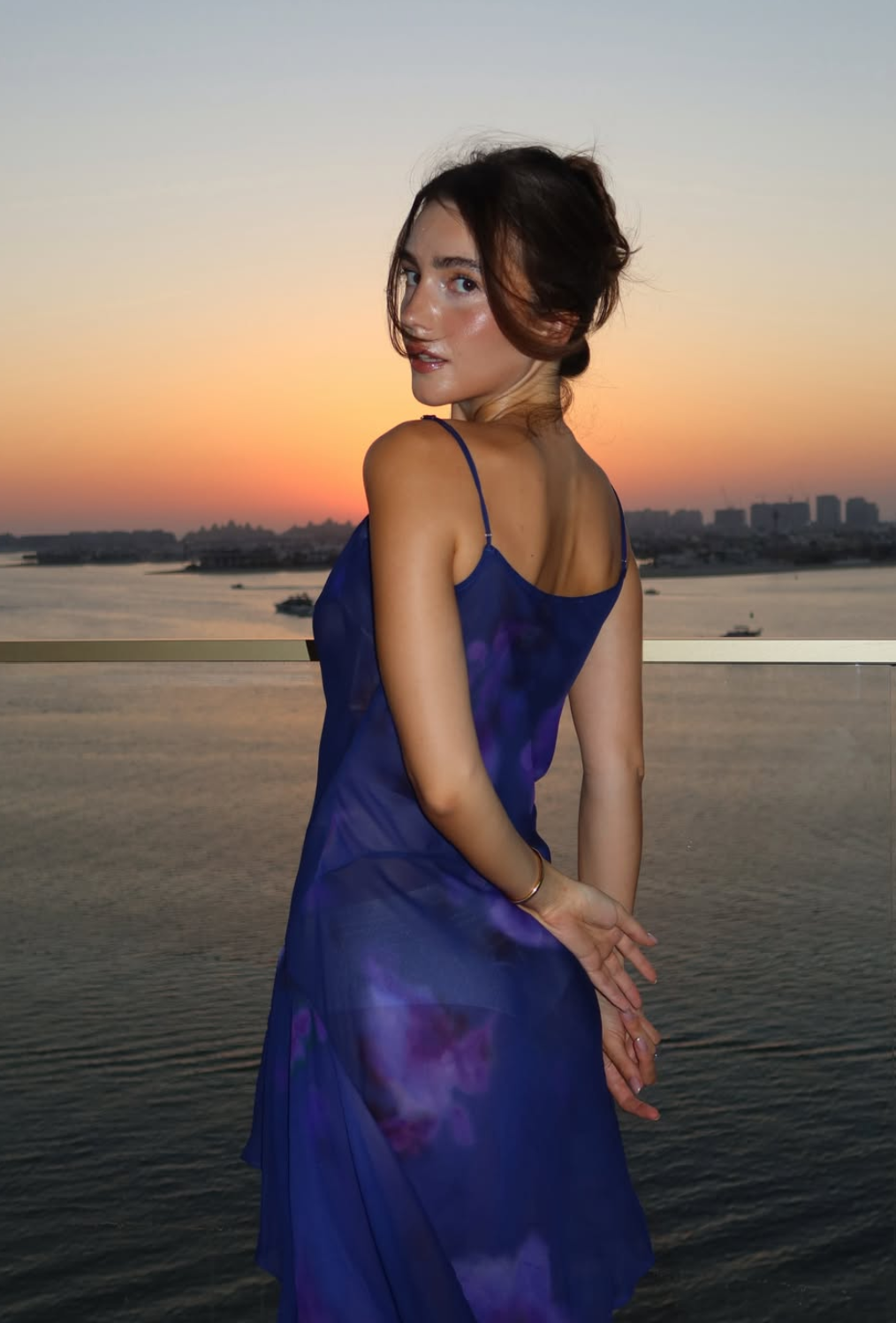 Tetiana Soviak in a purple dress at sunset overlooking the water