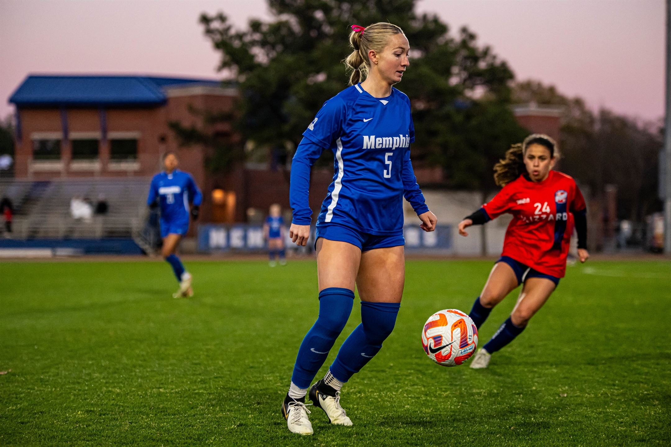 Macee McKenna in a Memphis blue #5 jersey controlling the ball at sunset