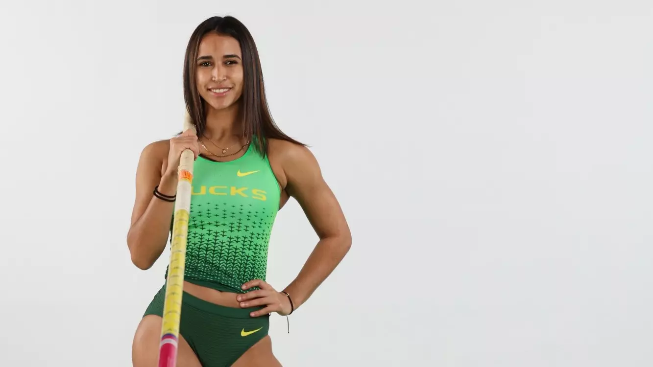 Bella Nilsen in a green Oregon Ducks track kit holding a pole vault pole