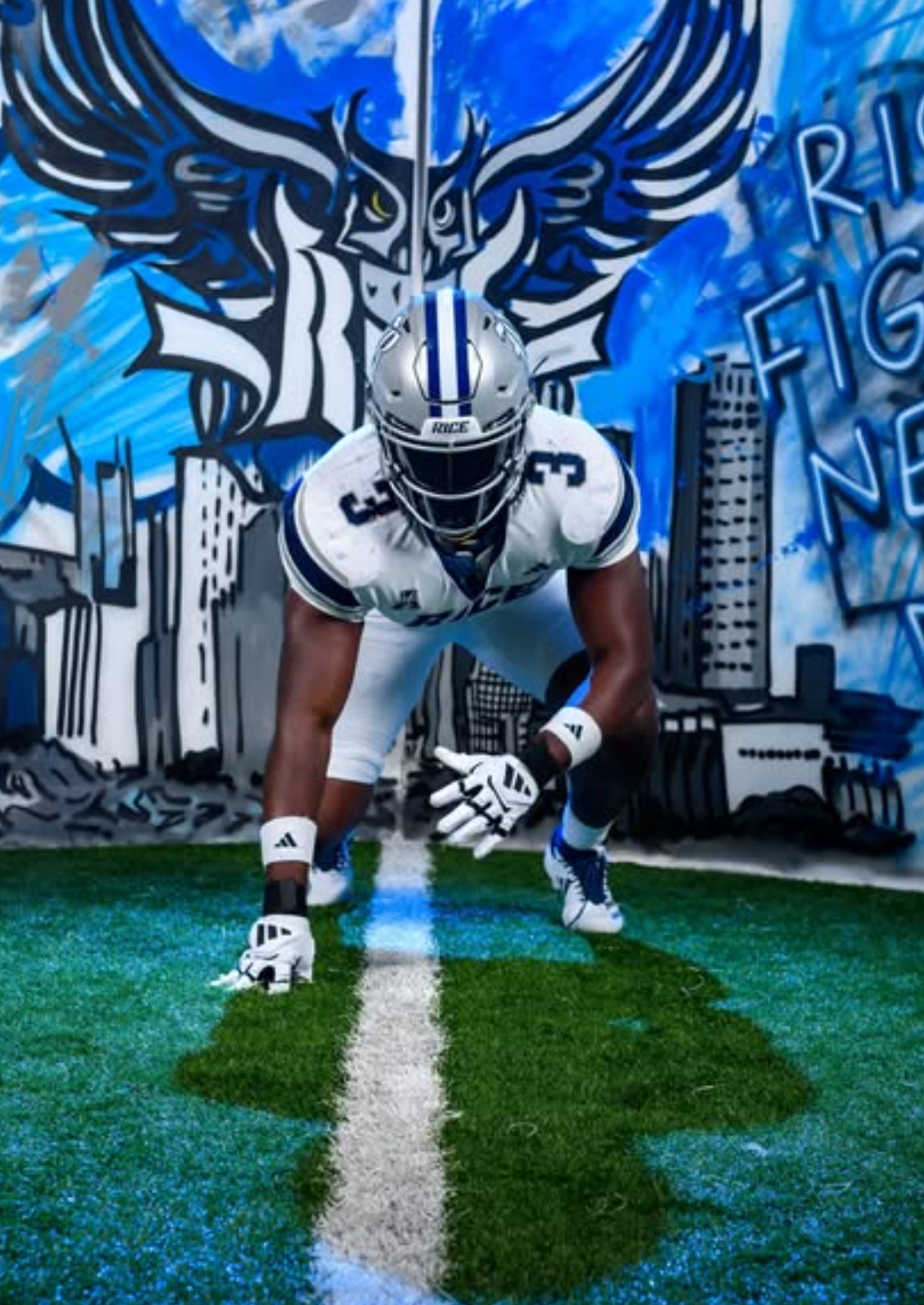 Quincy Tchikou in a three-point stance on turf in front of a blue Rice owl mural