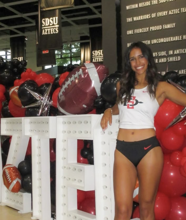 Bella Nilsen at the SDSU Aztecs spirit display with red and black balloons