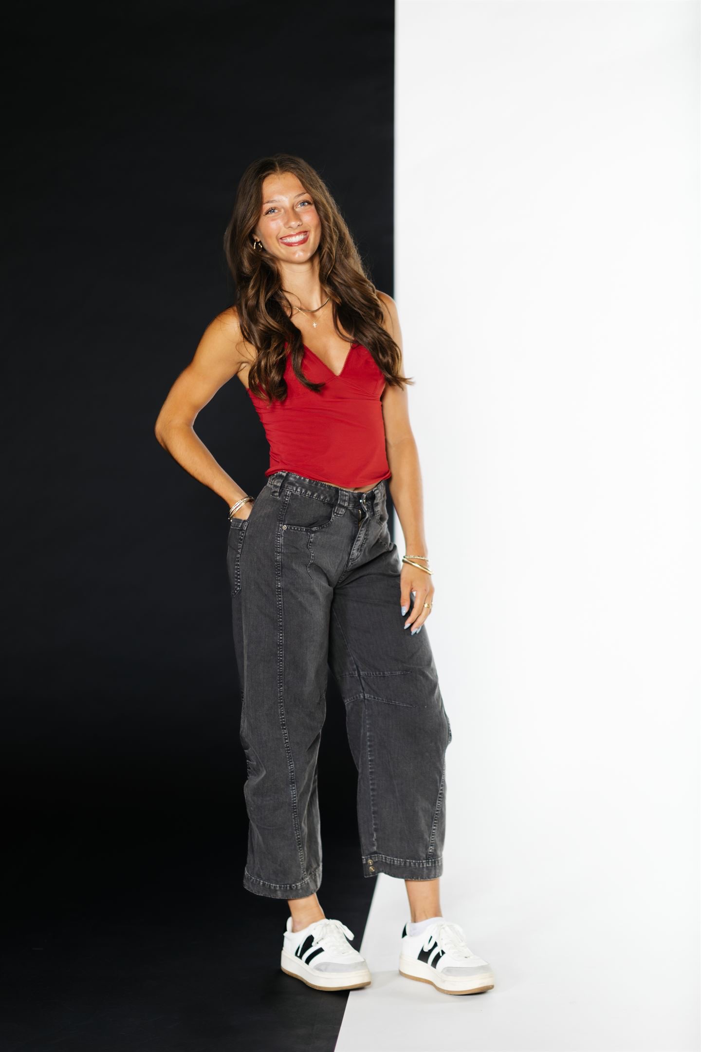 Logan Bell in a red top and black jeans against a split studio backdrop