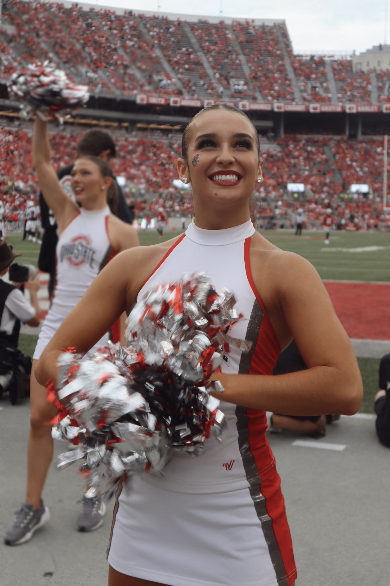 Emma Hellenkamp smiling on the Ohio State football sideline in a white dance uniform