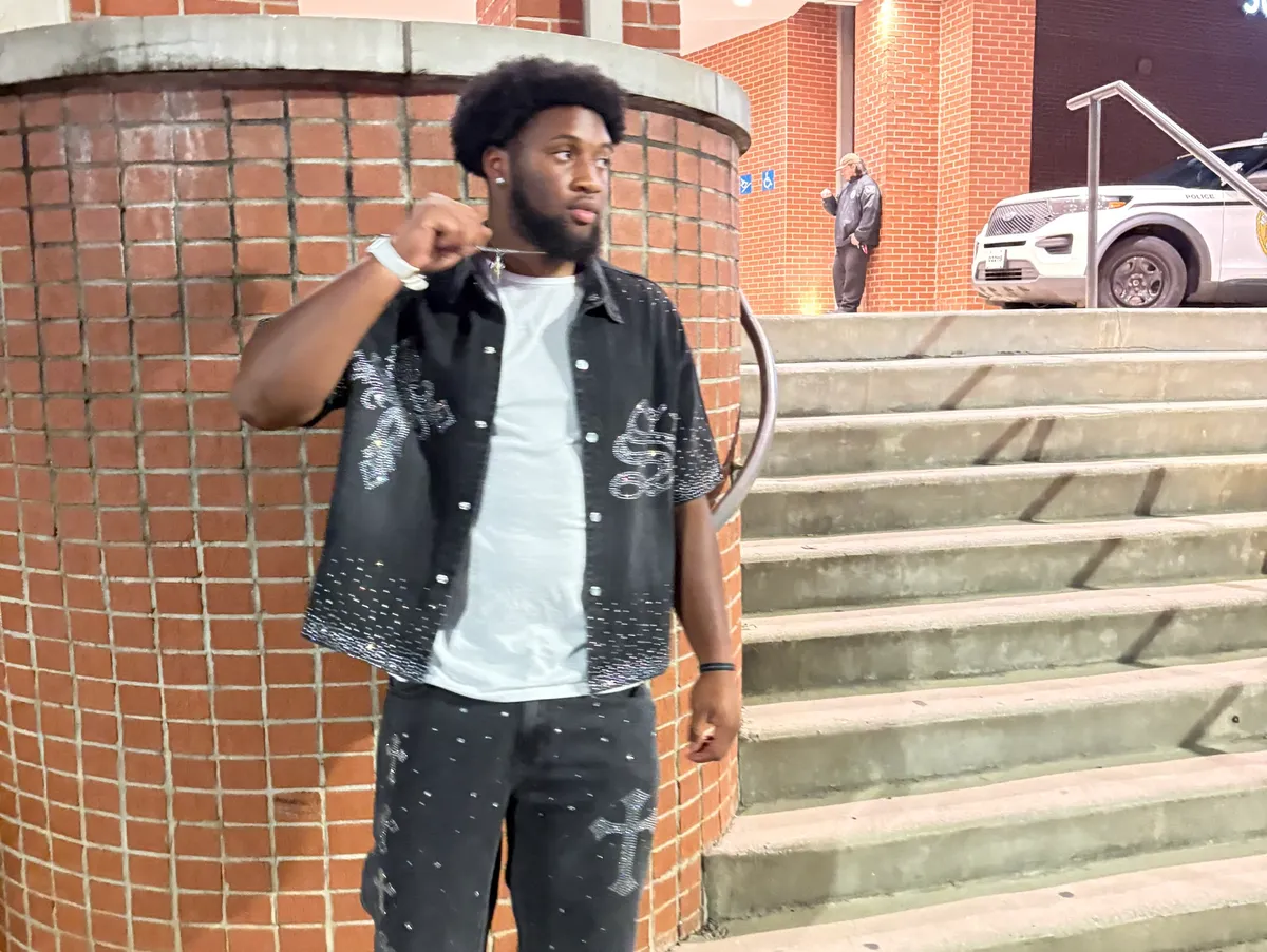 Andre Tibbs Jr in a black outfit beside brick steps at night