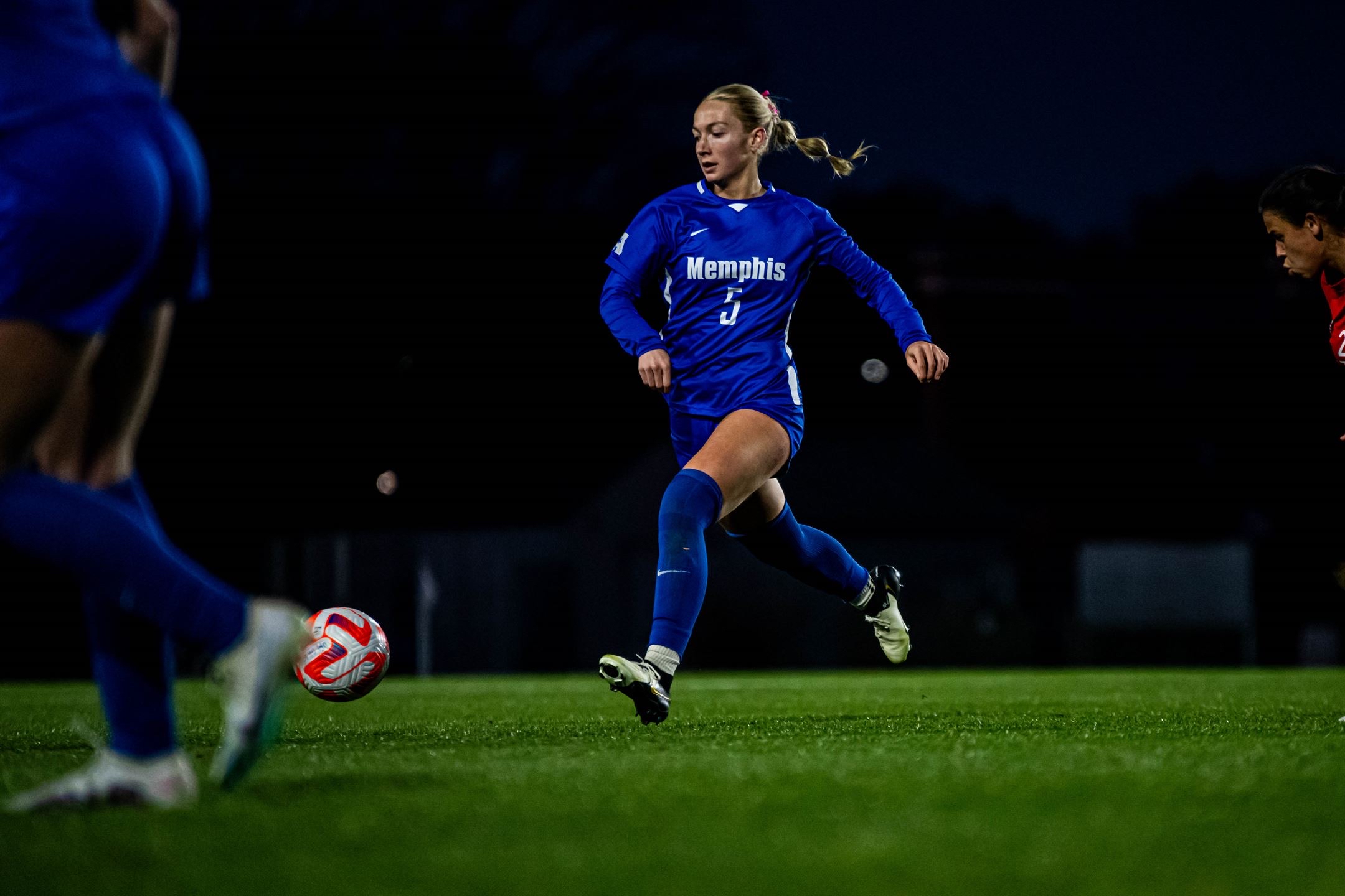 Macee McKenna in a Memphis #5 jersey driving down the field under the lights