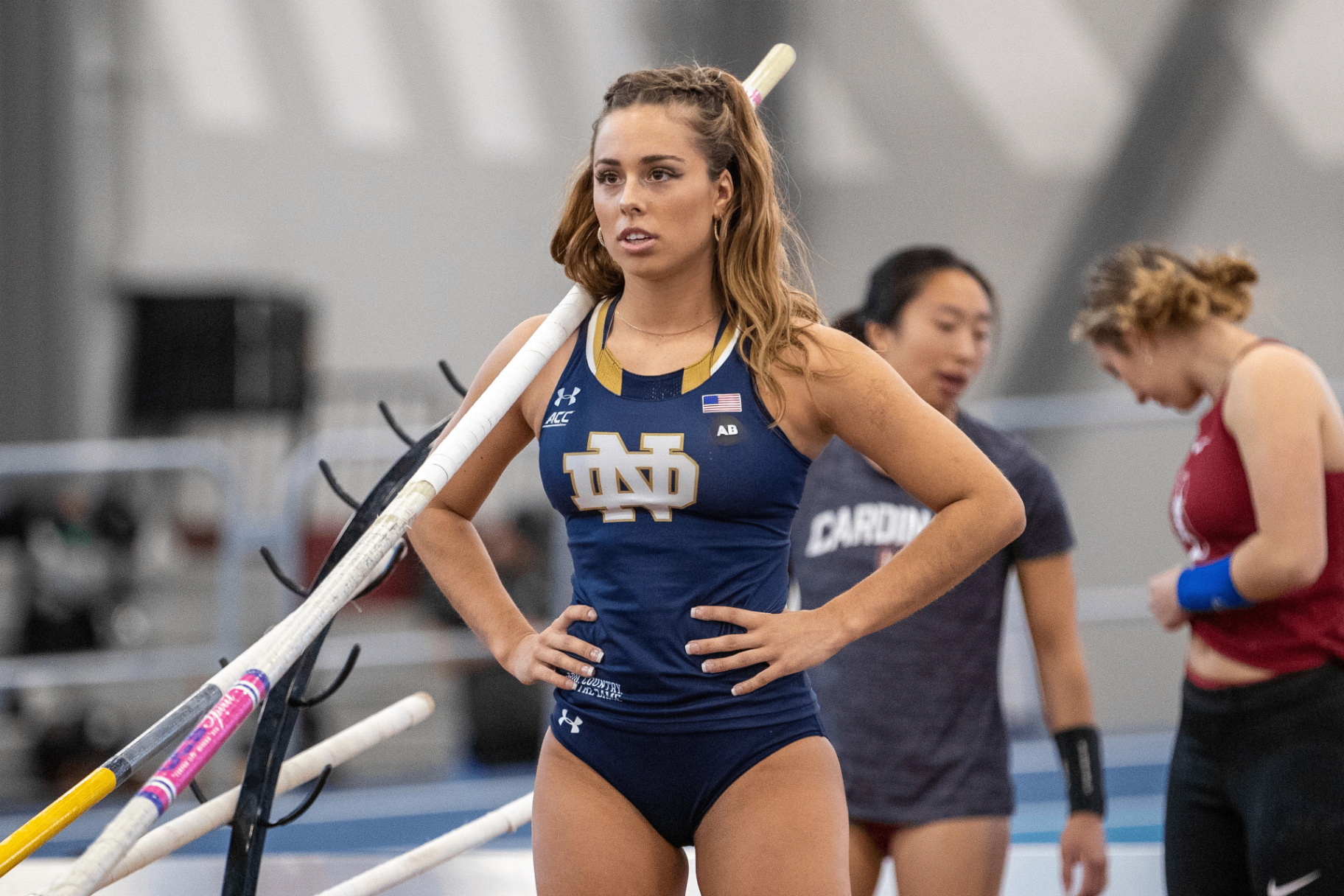 Olivia Fabry in a Notre Dame ACC track kit holding poles between vault attempts