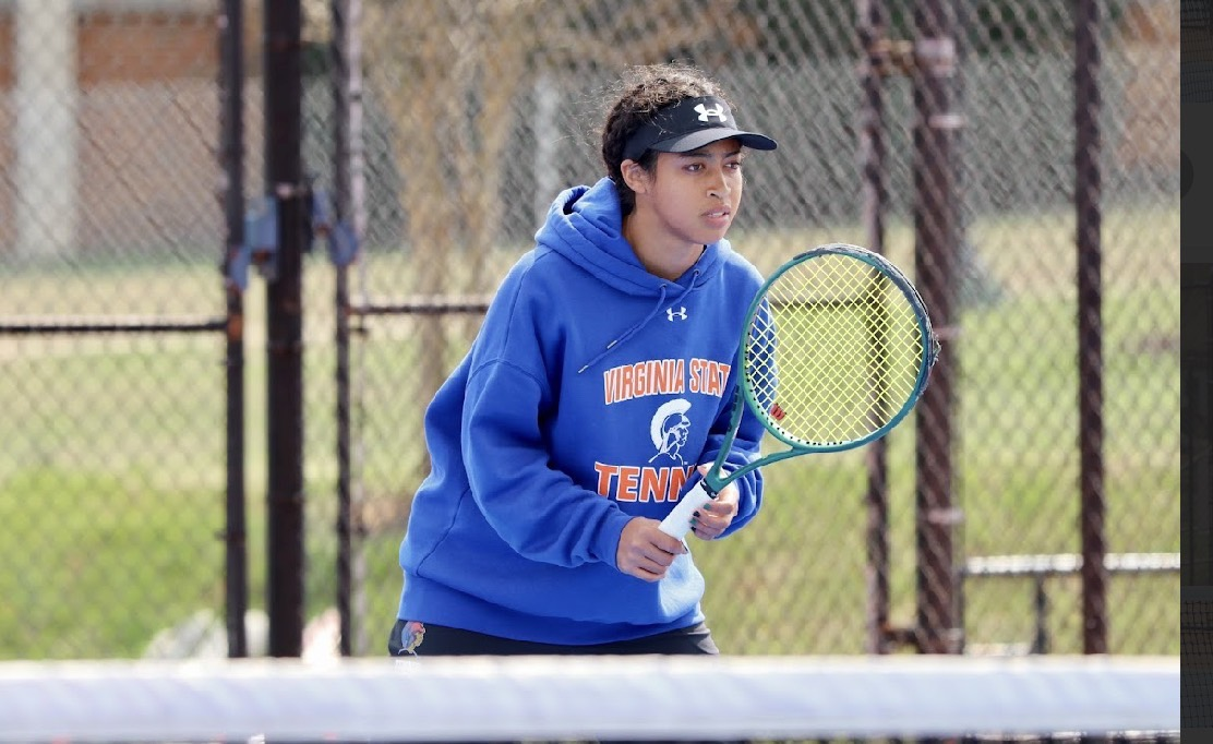 Leilani Hereford in a Virginia State Tennis hoodie in the ready position on the baseline